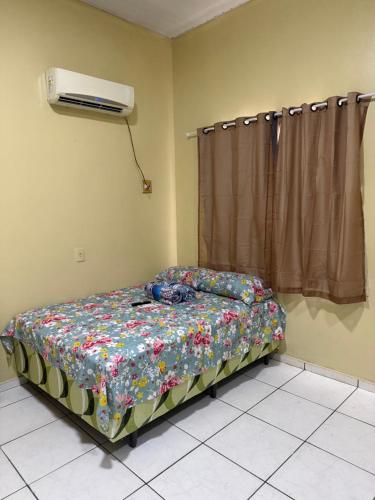 a bedroom with a bed with a floral comforter and a fan at Guest House da Amazônia in Manaus