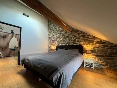 a bed in a room with a stone wall at La grange de Tom in Marche-en-Famenne