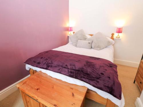 a bedroom with a bed with a purple blanket on it at Natures Retreat in Matlock