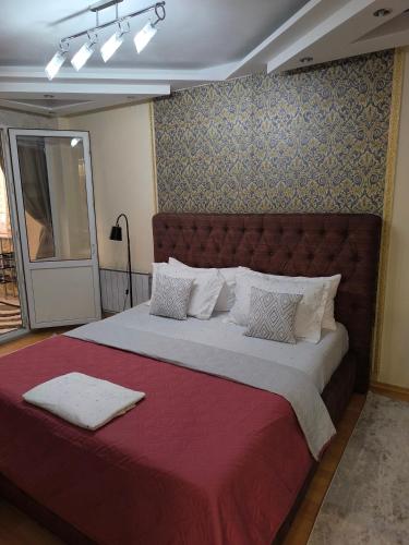 a bedroom with a large bed with a red headboard at Апартаменты на Бараева in Astana