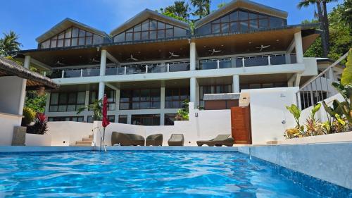 a large building with a swimming pool in front of it at Iluka 2- By the Bay in Puerto Galera