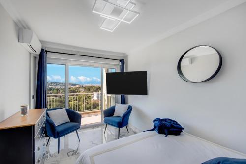 a bedroom with a bed and two chairs and a mirror at Panorama Majestic in Saint-Raphaël