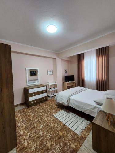 a bedroom with a bed and a desk and a television at Jozi Kaiser Apartment 4 in Durrës