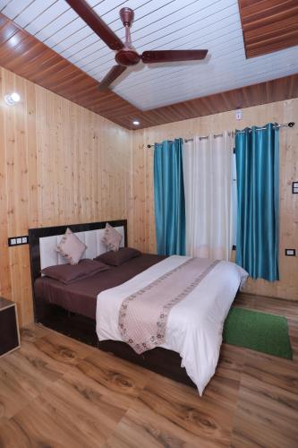 a bedroom with a bed with a ceiling fan at Brahamkamal Resort in Gupta Kāshi