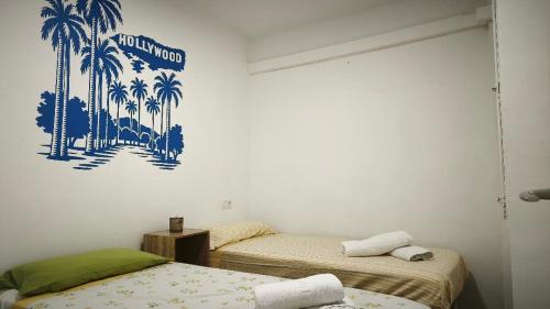 two beds in a room with palm trees on the wall at Hollywood Palazzo in Roses