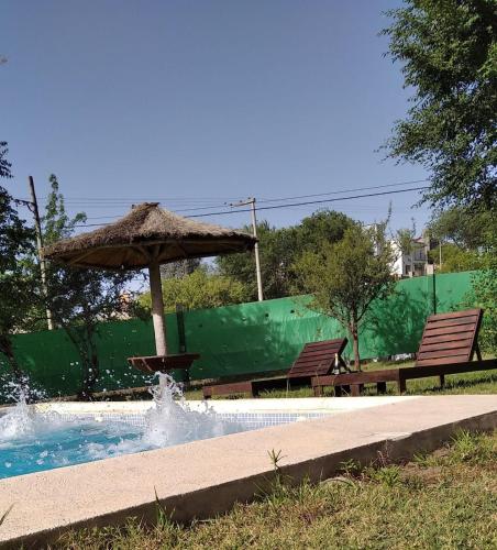 a pool with an umbrella and two benches at Casa brisas del rey in San Antonio de Arredondo