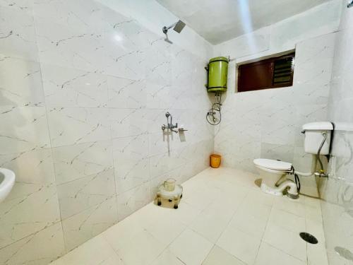 a white bathroom with a toilet and a sink at Hotel Rana Taradevi in Shimla