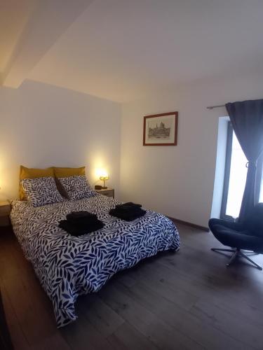 a bedroom with a bed and a chair and a window at Le Bredele in Riquewihr