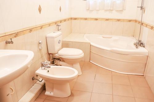 a bathroom with a toilet and a sink and a bath tub at Kandy downtown villa Monza in Bahirawakanda
