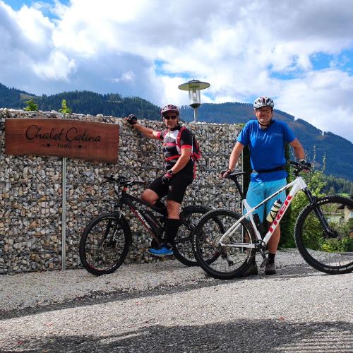 two men standing next to their bikes next to a stone wall at Chalet Catina in Bad Kleinkirchheim