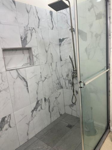 a shower with a glass door in a bathroom at Cozy Modern flat in Tunapuna