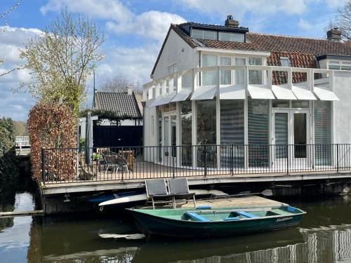 a house on a dock with a boat on the water at Lovely house on the water near Amsterdam in 's-Graveland
