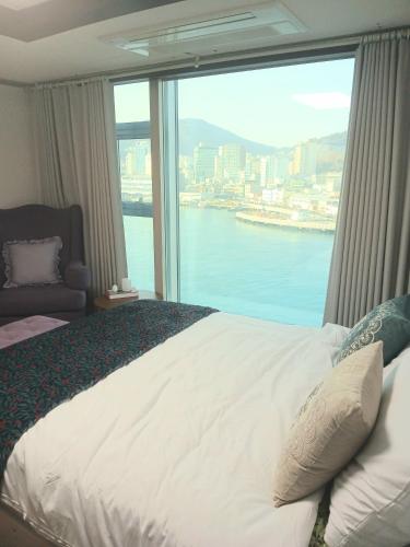 a bedroom with a large window with a view of the water at 부산남포 프론트오션뷰 in Busan