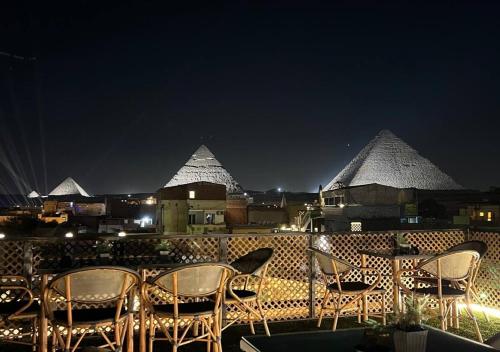 a group of chairs and tables on a balcony at night at Nefertari Pyramids View Inn in Cairo