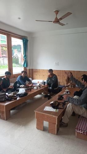a group of men sitting at tables in a room at Himalayan bite pulga in Kalgha