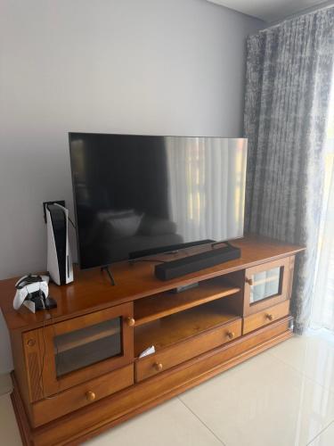 a flat screen tv sitting on top of a wooden entertainment center at Masakwe BNB in Soweto