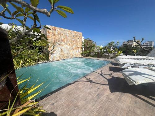 a swimming pool on a wooden deck with lounge chairs at Hotel Colibrí Suites in Porlamar