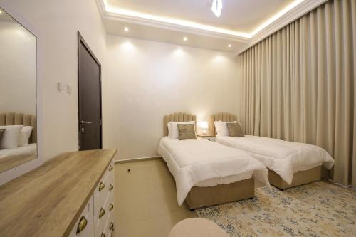a hotel room with two beds and a dresser at Silk Valley – Beachfront 3BR near Al Hamriyah in Sharjah