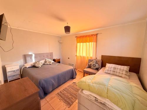 a bedroom with two beds and a couch and a window at Hospedaje Amore per il lago in Villarrica