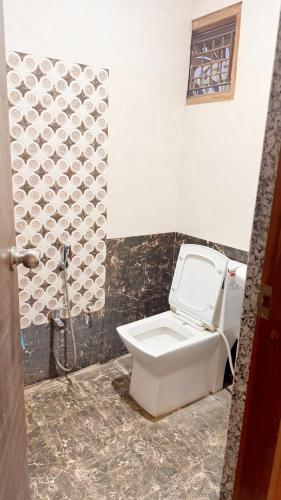 a bathroom with a white toilet and a wall at Pragati Guest House in Gorakhpur