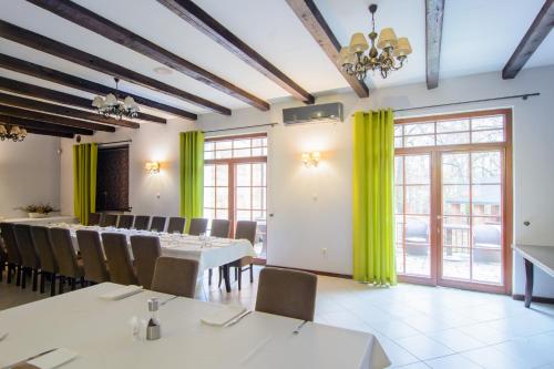 a dining room with tables and chairs and green curtains at Dworek Biały Domek in Smardzewice