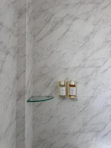 two bottles of essential oils on a white marble wall at Hotel Açores Premium- 5 minutos do Moinhos de Vento in Porto Alegre