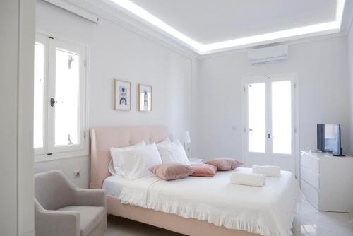a white bedroom with a bed and a chair at Modern Sea-View Maisonette in Spetses for 6 people in Spetses