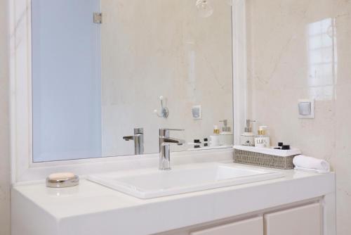 a white bathroom with a sink and a mirror at Modern Sea-View Maisonette in Spetses for 6 people in Spetses