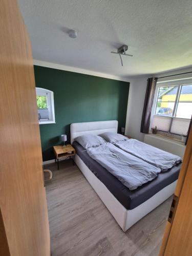 a bedroom with a bed and a green wall at Thirty Minutes in Ellingstedt
