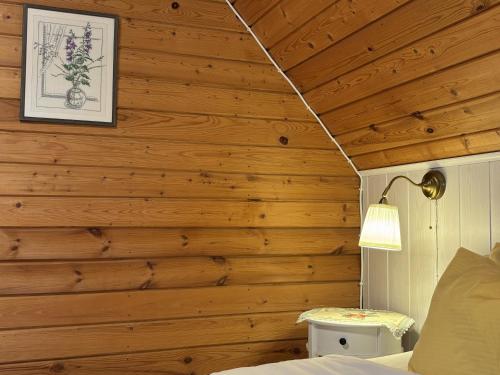 a bedroom with wooden walls and a bed with a lamp at Sarapuu puhkemaja in Hullo