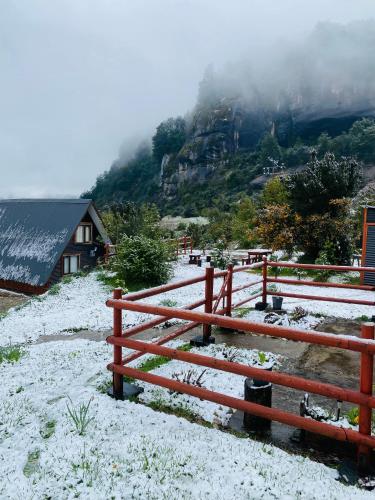 a snow covered hill with a fence and a house at CABAÑA PARCELA VISTA HERMOSA in Puerto Aisén