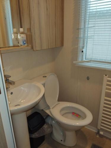 a bathroom with a toilet and a sink at Sunny sands retreat in Skipsea