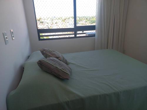 a bed with two pillows on it with a window at Villas House - Praia Formosa - Cabedelo in Cabedelo