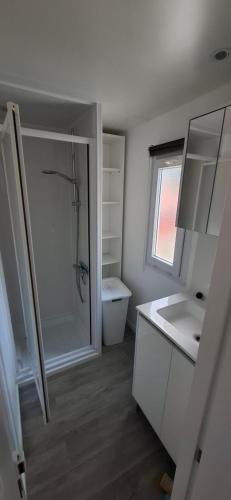 a white bathroom with a shower and a sink at Mobil home proche Fréjus - Camping 4 étoiles in Puget-sur-Argens