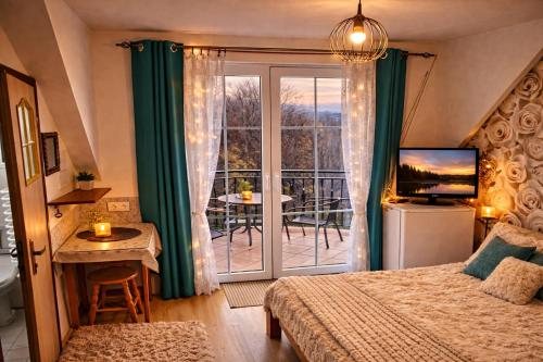 a bedroom with a bed and a balcony with a table at Domki i Pokoje nad Soliną in Polańczyk