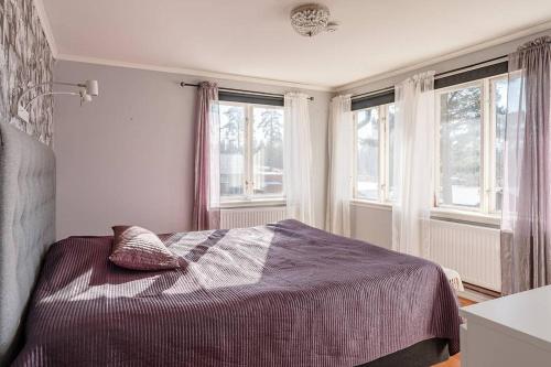 a bedroom with a bed and two windows at Slätterne Gård B&B in Sandviken