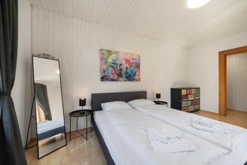 a bedroom with a large white bed and a mirror at Apartment Troya in Unterseen