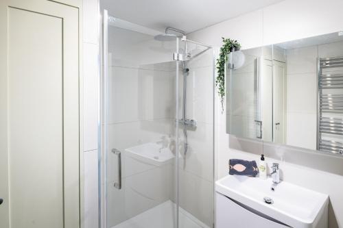 a white bathroom with a shower and a sink at Modern Flat on the seafront Exmouth in Exmouth