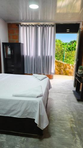 a bedroom with a bed and a large window at Green Apartment el prado in Girón
