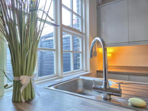 a kitchen sink with a vase with a plant next to a window at The Indigo Escape in Ibstock