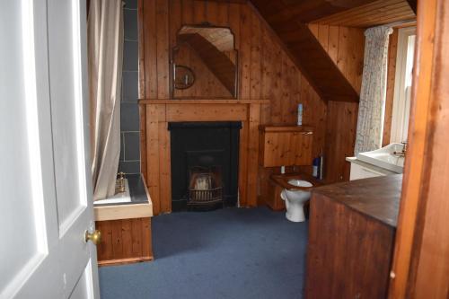 a bathroom with a fireplace in a wooden house at The Loan in Achiltibuie