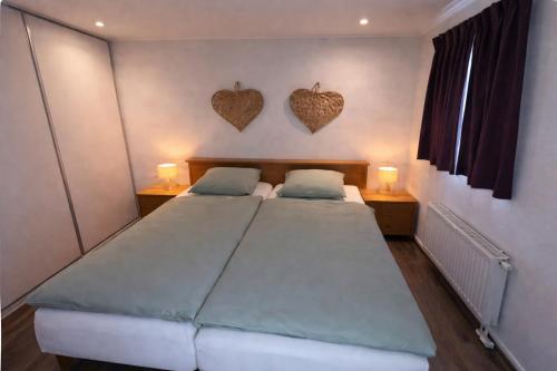 a bedroom with two beds and two hearts on the wall at 't Vrolijke Uusje in Scharendijke
