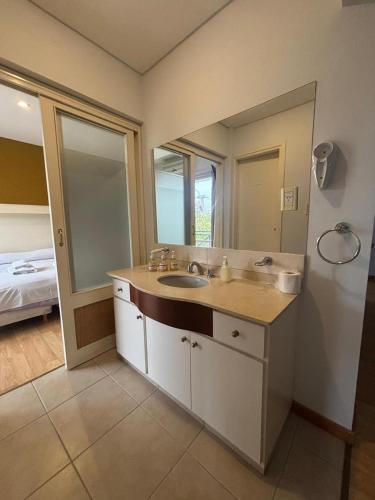 a bathroom with a sink and a large mirror at Soleado Apart Hotel in San Rafael