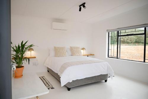 a white bedroom with a bed and a window at Landskap in Robertson