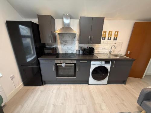 a kitchen with a washing machine and a washer at Sleek 1BR Flat Perfect Getaway For Contractors Or Couples in Cardiff
