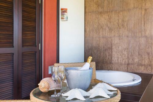 a bathroom with a tub and a table with wine glasses at Refúgio das Galés Mariscal in Bombinhas