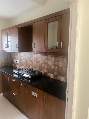 a kitchen with wooden cabinets and a stove top at HK villas in Edappally