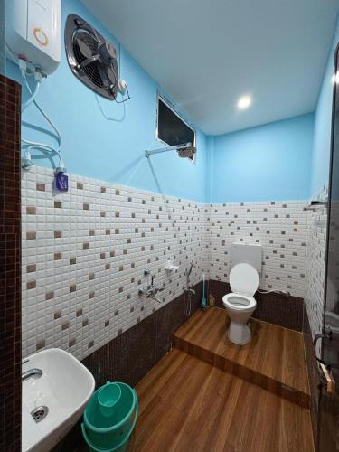 a bathroom with a white toilet and a sink at Vasudha Homestay in Sibsāgar
