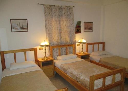 a bedroom with three beds and two lamps on tables at Kareem Hotel Luxor in Luxor