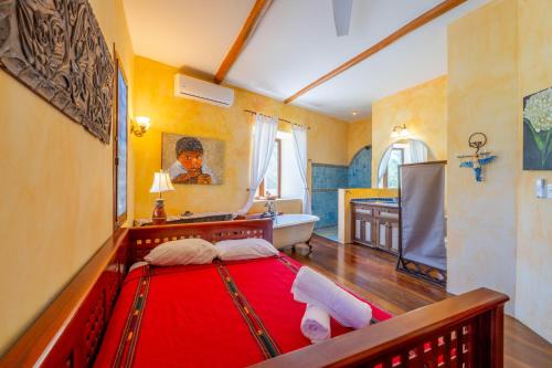 a bedroom with a red bed and a bath tub at La Perla del Caribe - Villa Opal in San Pedro